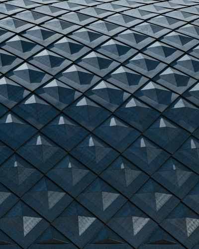 Close-up of a modern building facade showing a geometric pattern with diamond shapes in shades of blue.